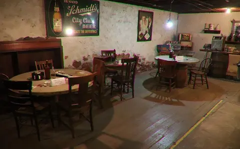 An interior view of a rustic room furnished with round wooden tables and chairs.