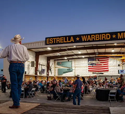 A crowd of people gathered inside a hangar for an event.