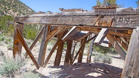 A weathered wooden structure stands in an arid outdoor setting.