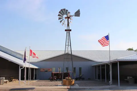 An exterior view of a building with a tall windmill and flags in front.