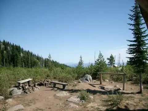 A scenic outdoor view of a forested landscape and campsite.