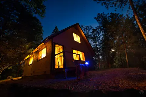 A house exterior at night with lit windows and a starry sky.
