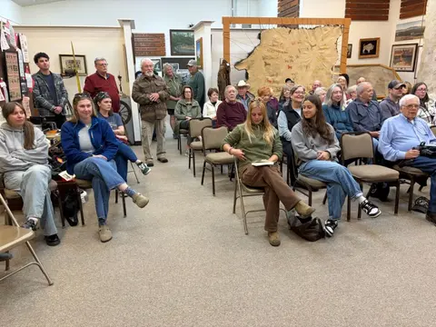 A group of people sitting and standing in a museum room.