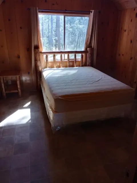 A rustic bedroom with wood paneling and a log bed frame.