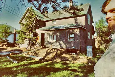 An exterior view of a multi-story house with construction in the yard.