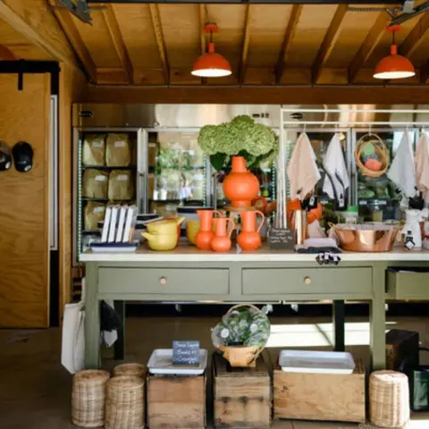 An interior shot shows a retail counter with orange pottery and green hydrangeas under pendant lights.