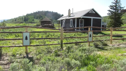 A rustic wooden cabin with a fence in the foreground.
