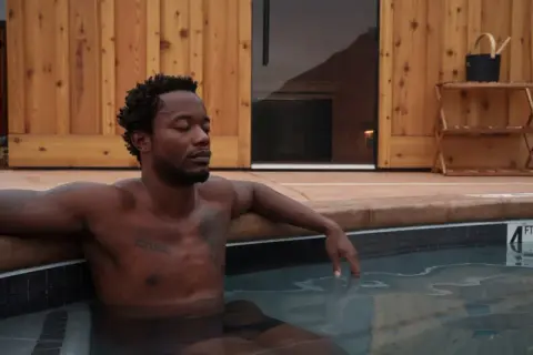 A man relaxes in a hot tub outdoors.
