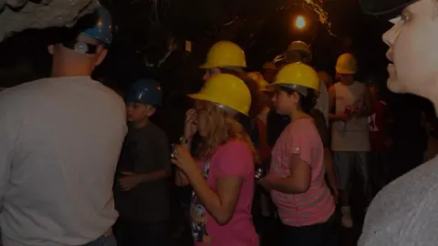 A group of people wearing hard hats inside a dark mine.