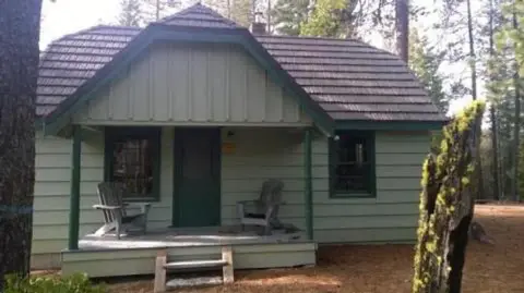 A small cabin with a front porch nestled among trees.