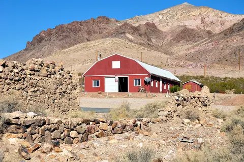 A red building stands in a desert landscape with mountains in the background.