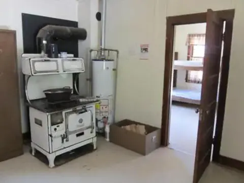 An interior view of a room with a vintage stove and a doorway leading to another room.