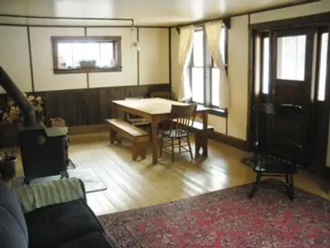 An interior view of a room with a wooden dining table and a stove.