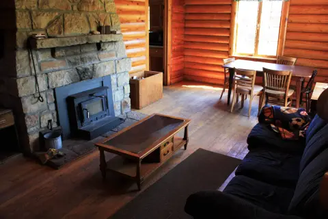 A rustic living room features a stone fireplace, a wooden coffee table, and a sofa.