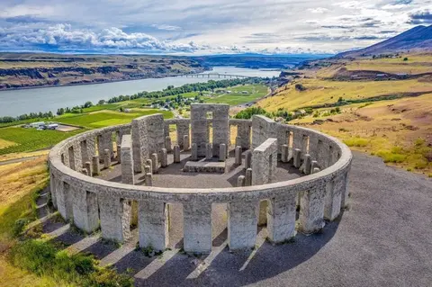 An aerial view of a stone circle structure overlooking a river and valley landscape.