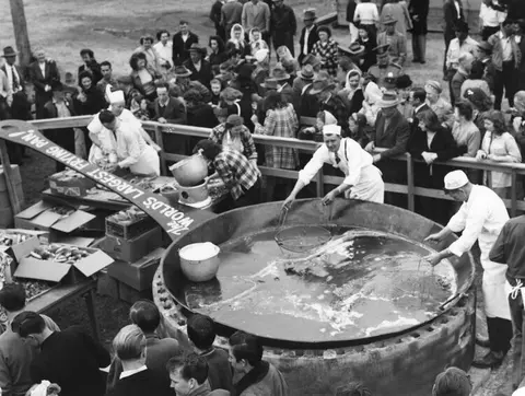 A historic photograph showing people gathered around a giant frying pan.