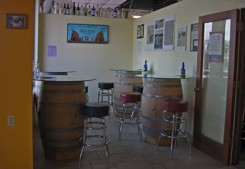 An interior view of a room featuring tall tables made from wooden barrels and matching stools.