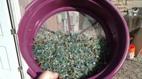 A purple sifter filled with small, colorful stones and gravel.