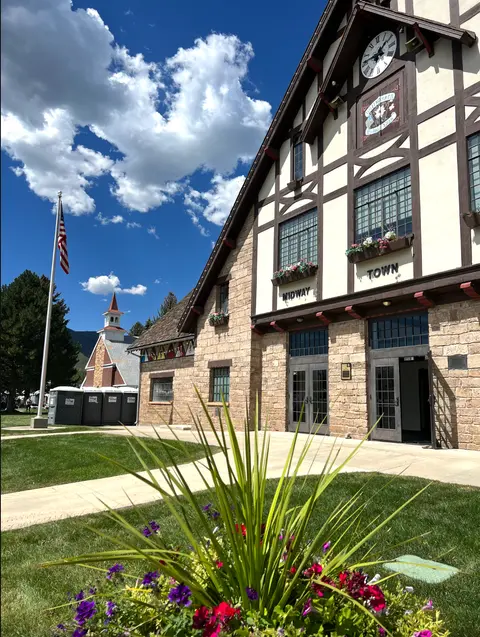 A large Tudor-style building with stone and half-timbering under a blue sky with fluffy clouds.
