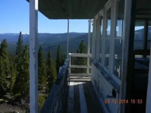 A view from the balcony of a fire lookout tower overlooking a forested landscape.