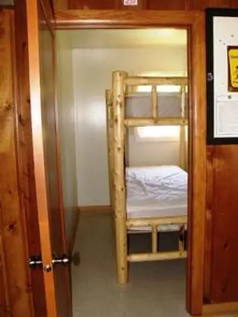 A view through a doorway into a small room with a wooden bunk bed.