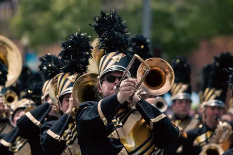 A marching band plays instruments during a parade.