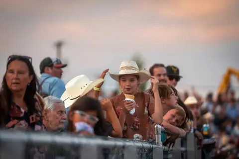 A crowd of people gathered behind a fence to watch an event.