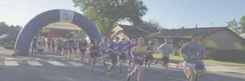 A group of runners approach the finish line arch during a race.