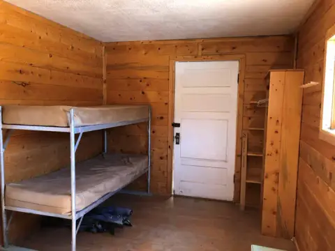 An interior shot of a rustic room with wooden walls and a bunk bed.
