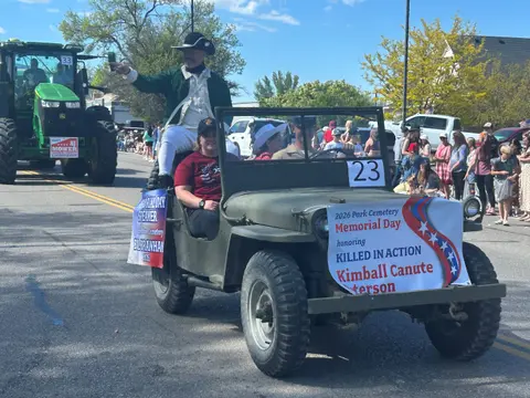 People in costume and vintage military vehicle participating in a parade on a street.