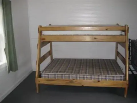 A wooden bunk bed with mattresses inside a room.