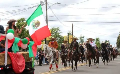 People ride horses and wave a flag in a parade.