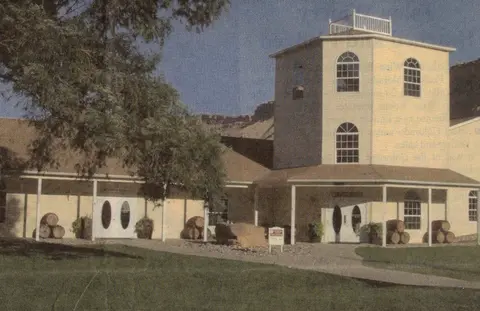 An exterior photo of a building surrounded by trees and lawn.