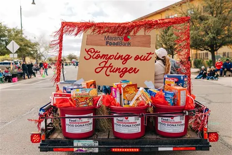 A parade trailer loaded with food donations and decorated with red tinsel.