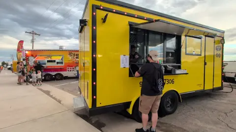 A customer ordering food at a yellow food truck.