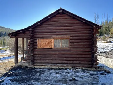Exterior view of a rustic log cabin in a snowy landscape.