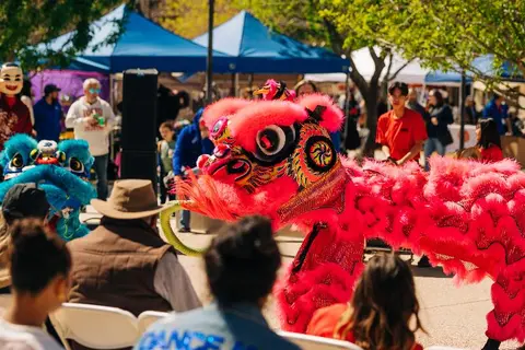 A colorful lion dance costume performs outdoors at an event.
