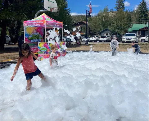 Children play in a large pile of foam outdoors.