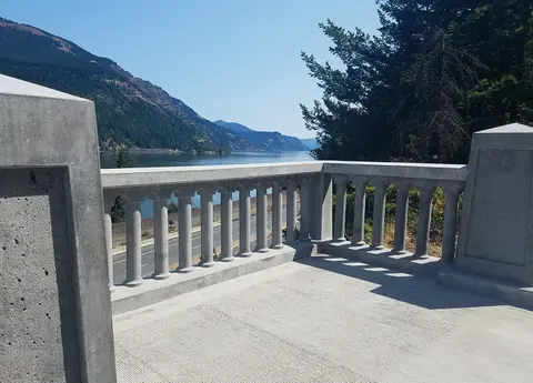 A concrete balcony overlooking a river and mountains.