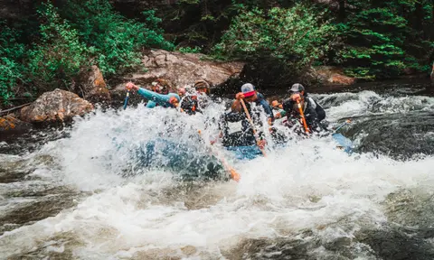 People white-water rafting through a rapid.