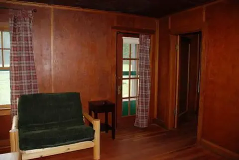 An interior room with wood-paneled walls and a green armchair.