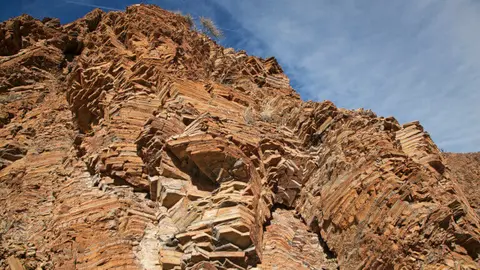 A close-up view of layered rock formations against a blue sky.