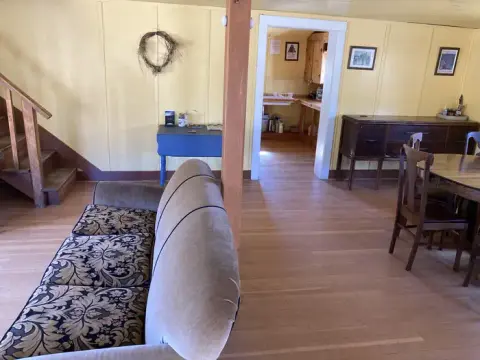 An interior view of a living room with a sofa and a view into another room.