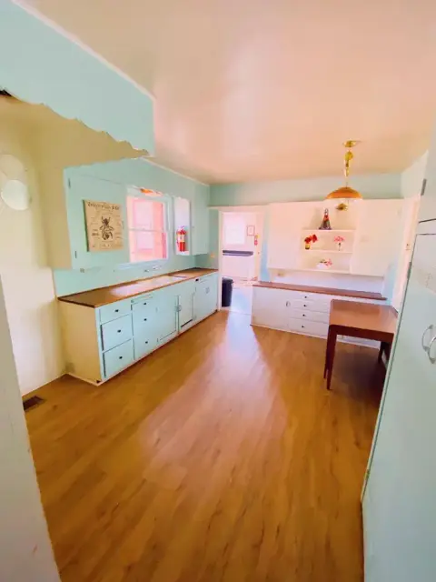 An interior shot of a kitchen with light blue cabinets and wood flooring.