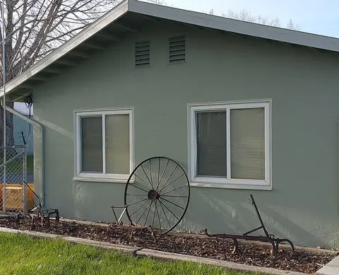 Exterior view of a green building with vintage farm equipment displayed in front.