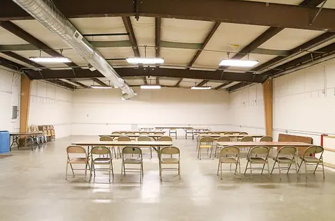 An interior view of a large room set up with tables and folding chairs.