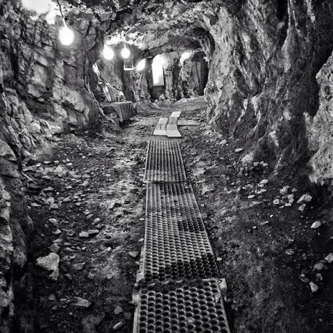 Black and white photo of a rocky cave or tunnel interior with a grated pathway.