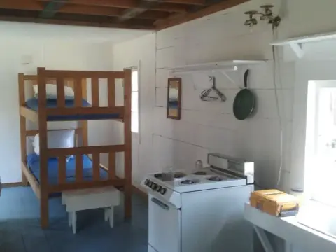 An interior view of a small rustic cabin with a bunk bed and a stove.
