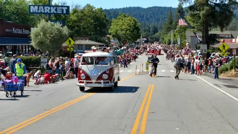 A parade with people and vehicles on a town street.