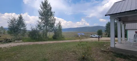 A scenic view of a grassy valley and mountains from a porch.